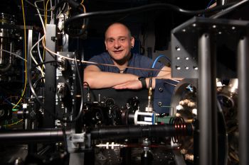 Professor Winfried Hensinger crossing his arms behind a prototype of a quantum computer in the quantum technologies lab at the Ƶ