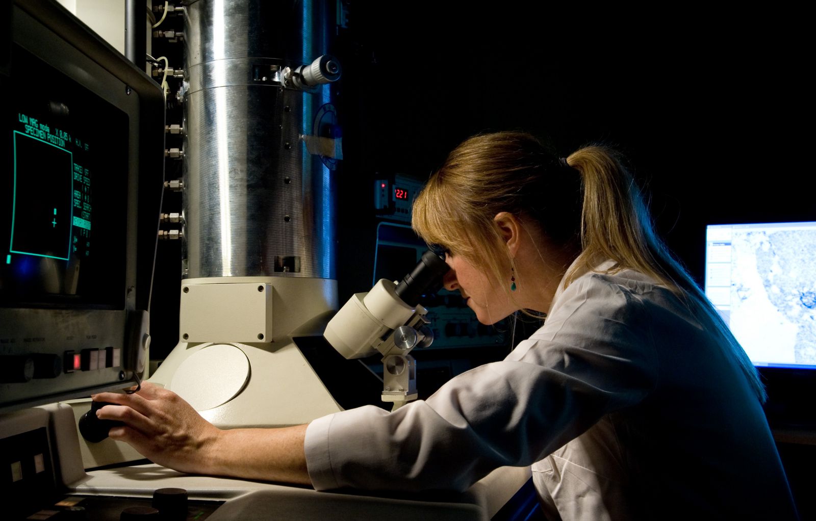 PhD student looks through a microscope in a science lab at the Ƶ